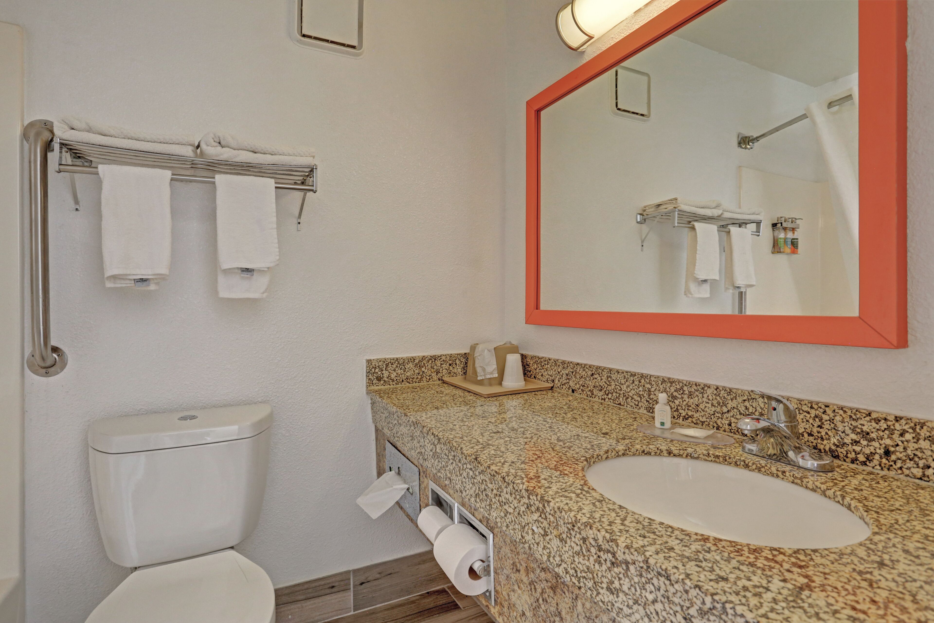 Un baño con inodoro, lavabo, espejo y toallero.