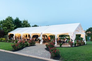 Outdoor event space with seating for guests, surrounded by well-manicured grass and a paved walkway.