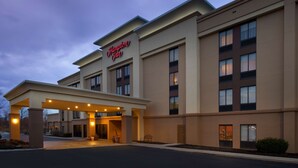 Ein Hampton Inn Hotel mit moderner Fassade, einem überdachten Eingang und einer gut beleuchteten Außenansicht.