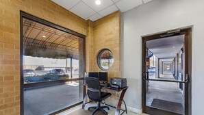 Ein Zimmer mit großem Fenster, einem Schreibtisch mit Computer und einer Tür zu einem Korridor.
