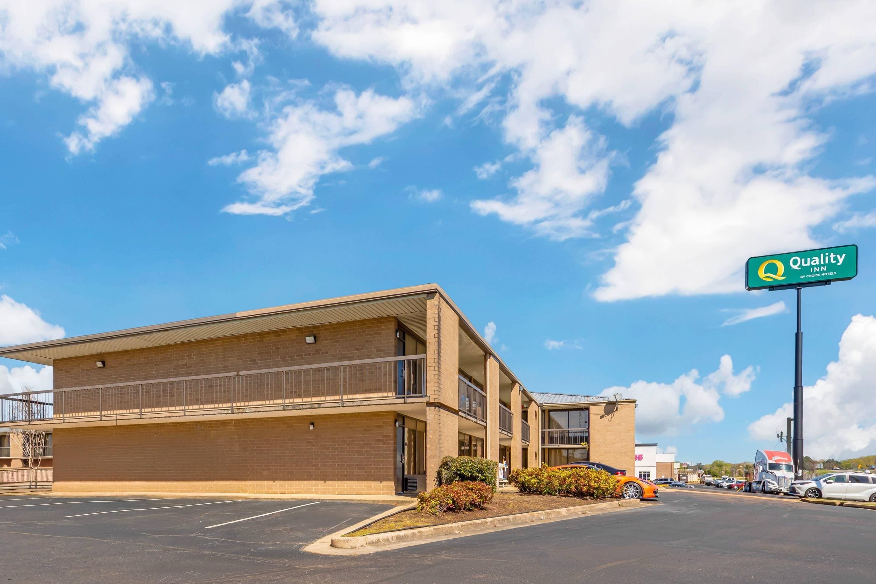 A two-story building with a parking lot, a Quality Inn sign, and a clear blue sky.