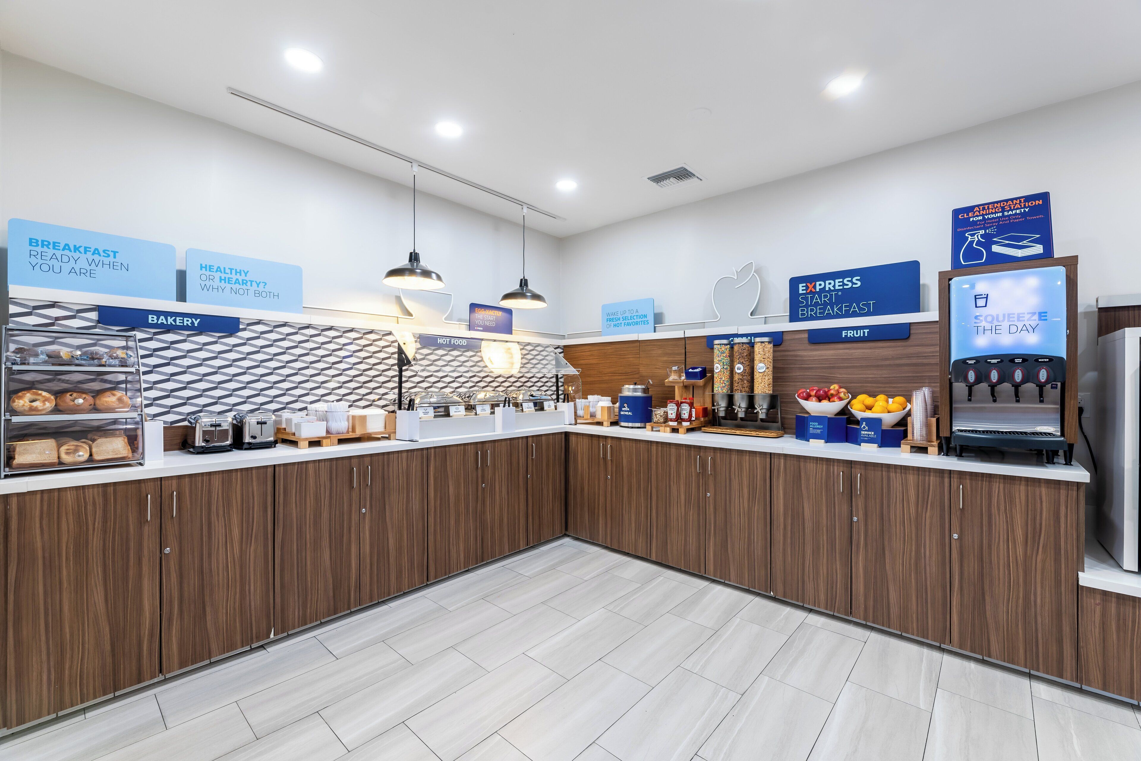 Un moderno espacio para el desayuno con panadería, comida caliente y una exhibición de frutas, además de una estación de café.