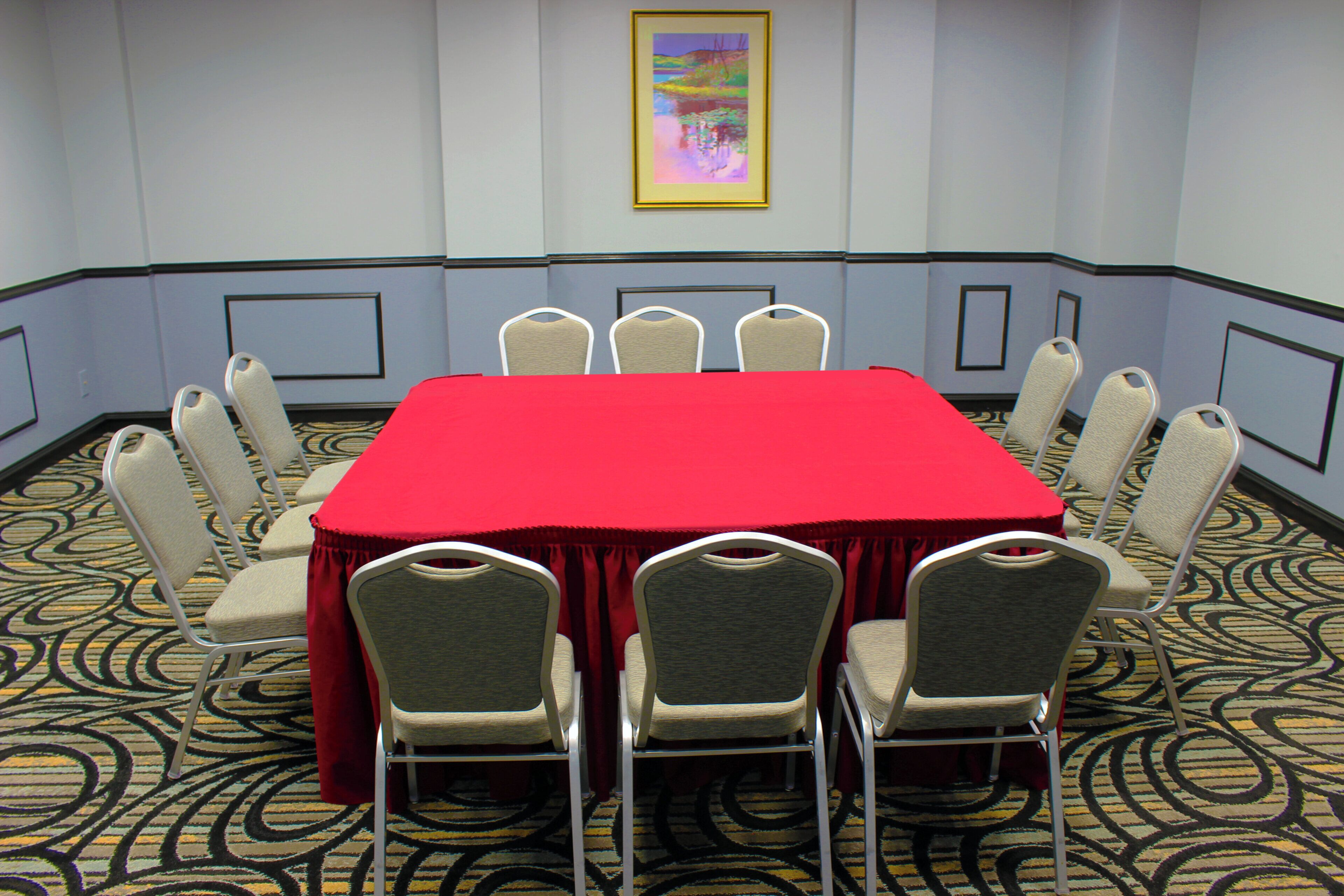 A conference room with a red table and eight chairs.
