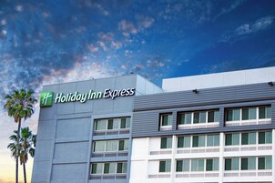 Ein Holiday Inn Express Gebäude mit einer modernen Fassade, großen Fenstern und blauem Himmel im Hintergrund.