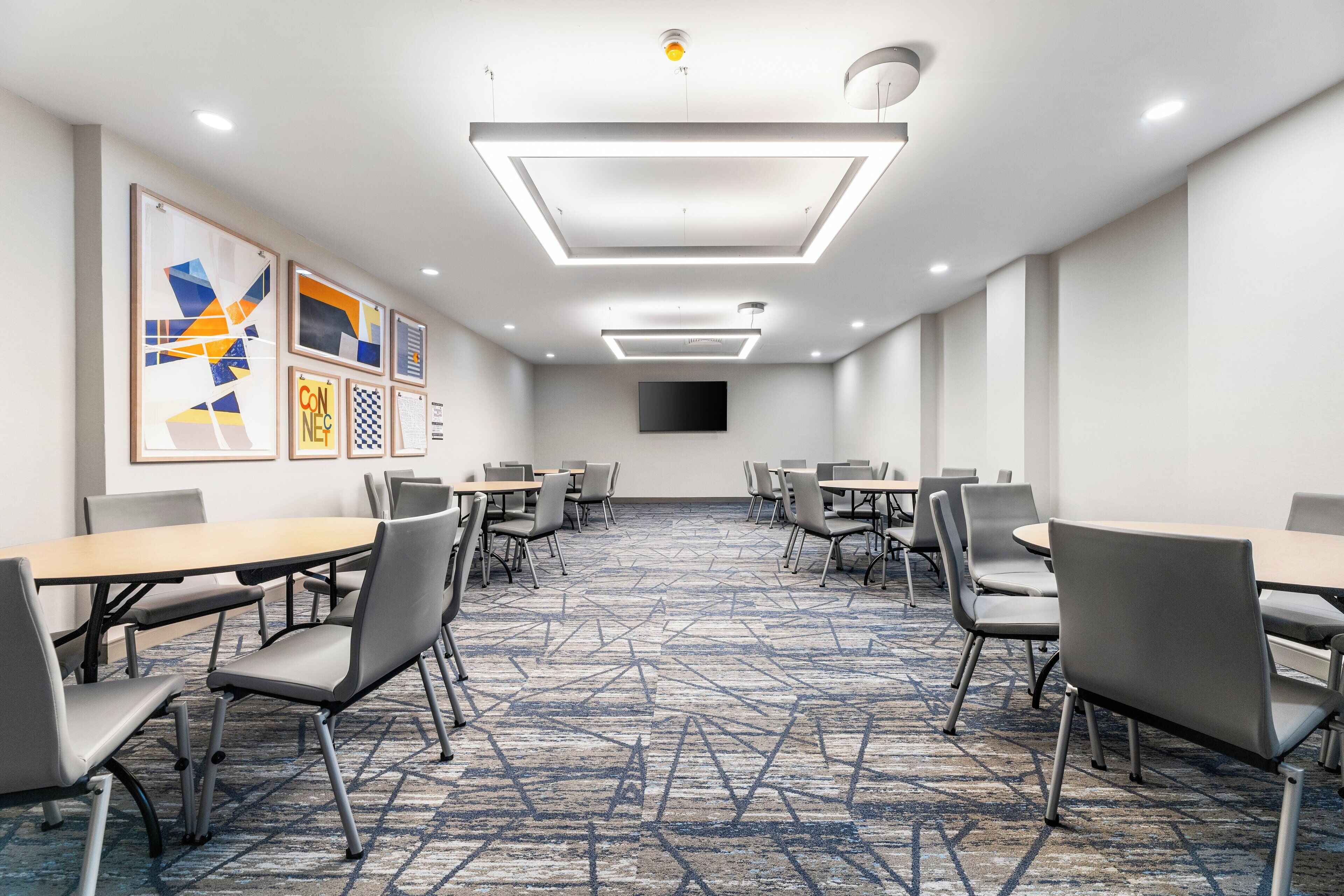 Een congreszaal met een geometrisch vloerkleed, moderne verlichting en lijstwerken aan de wanden.
