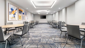 Une salle de conférence dotée d’un tapis aux motifs géométriques, d’un éclairage moderne et d’œuvres d’art encadrées accrochées aux murs.
