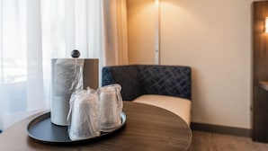 Une chambre d’hôtel avec une table ronde en bois, une lampe et un coin salon avec des fauteuils confortables.