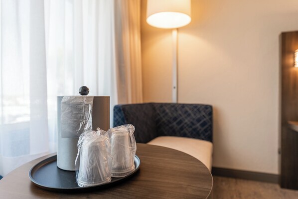 A hotel room with a round wooden table, a lamp, and a cushioned seating area. - Holiday Inn Express Van Nuys by IHG (Van Nuys)