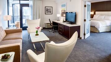 A hotel room with a sofa, a desk with a computer, a television, and a bed.