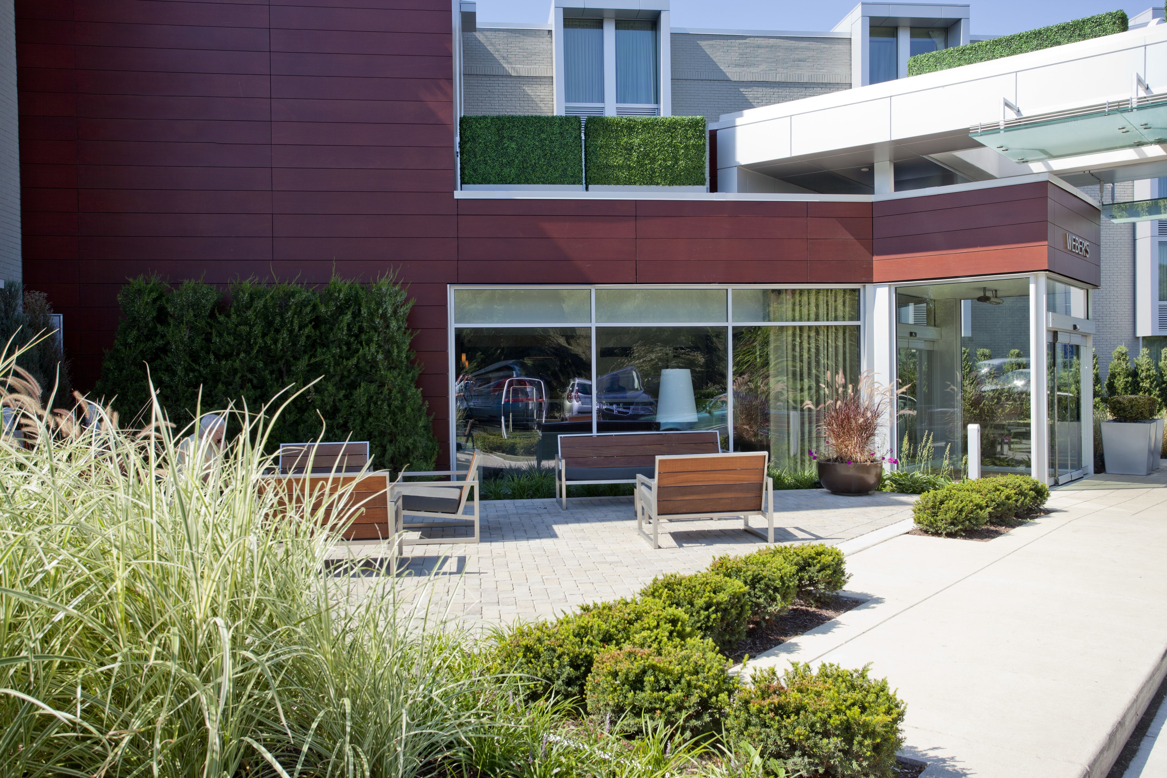 Un bâtiment moderne doté d’une entrée en verre, d’une terrasse et d’un jardin sur le toit.