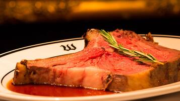 A plate of sliced roast beef with a sprig of rosemary on top, served on a white plate with a black rim.