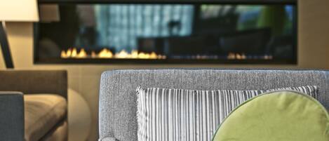 A modern living room with a fireplace, a sofa, and a striped cushion.