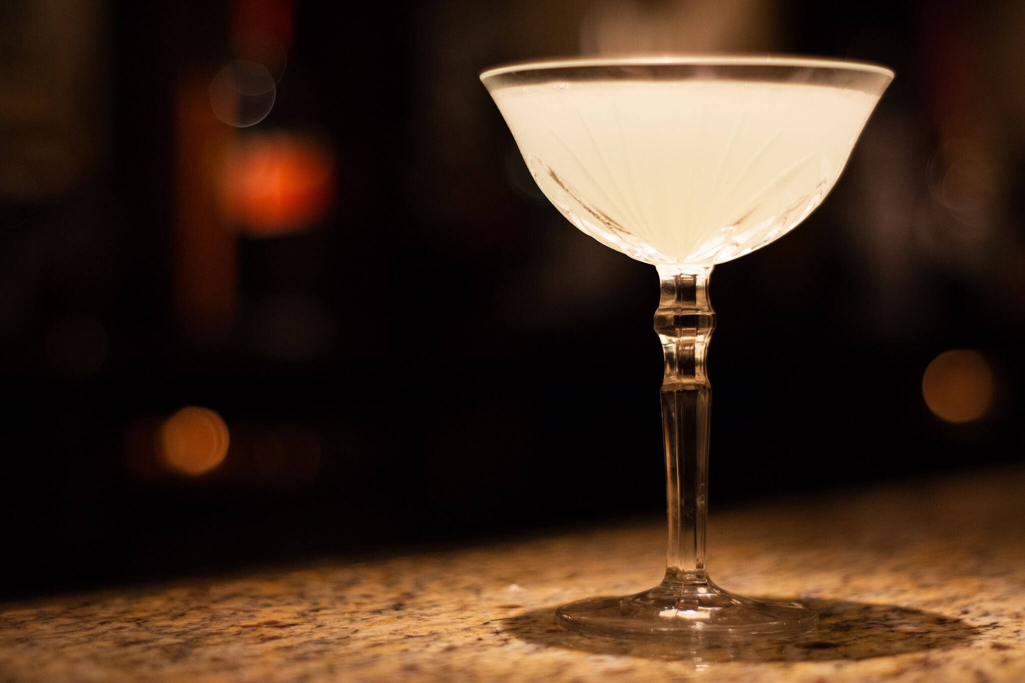 A martini glass on a granite countertop.