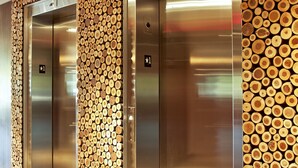 Two elevator doors with a wall of stacked logs between them. - Weber's Hotel & Restaurant (Ann Arbor)