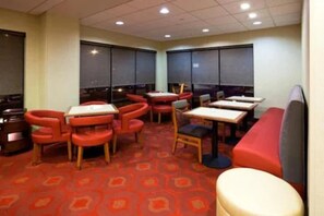 A restaurant with red and beige seating, large windows, and a patterned carpet. - Hampton Inn Rockford (Rockford)