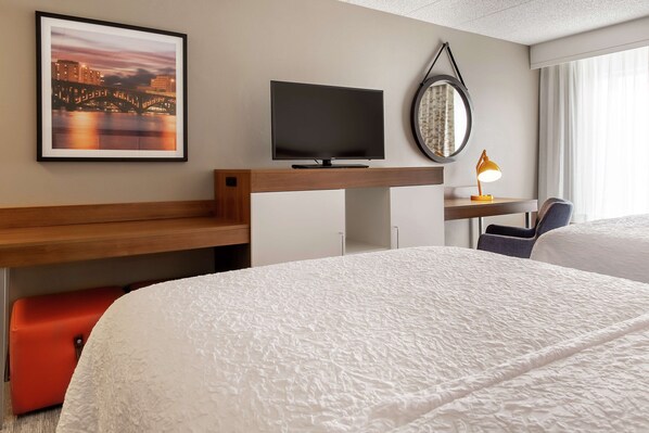 A hotel room with a bed, a desk with a computer, a television, a mirror, and a framed picture of a bridge. - Hampton Inn Rockford (Rockford)