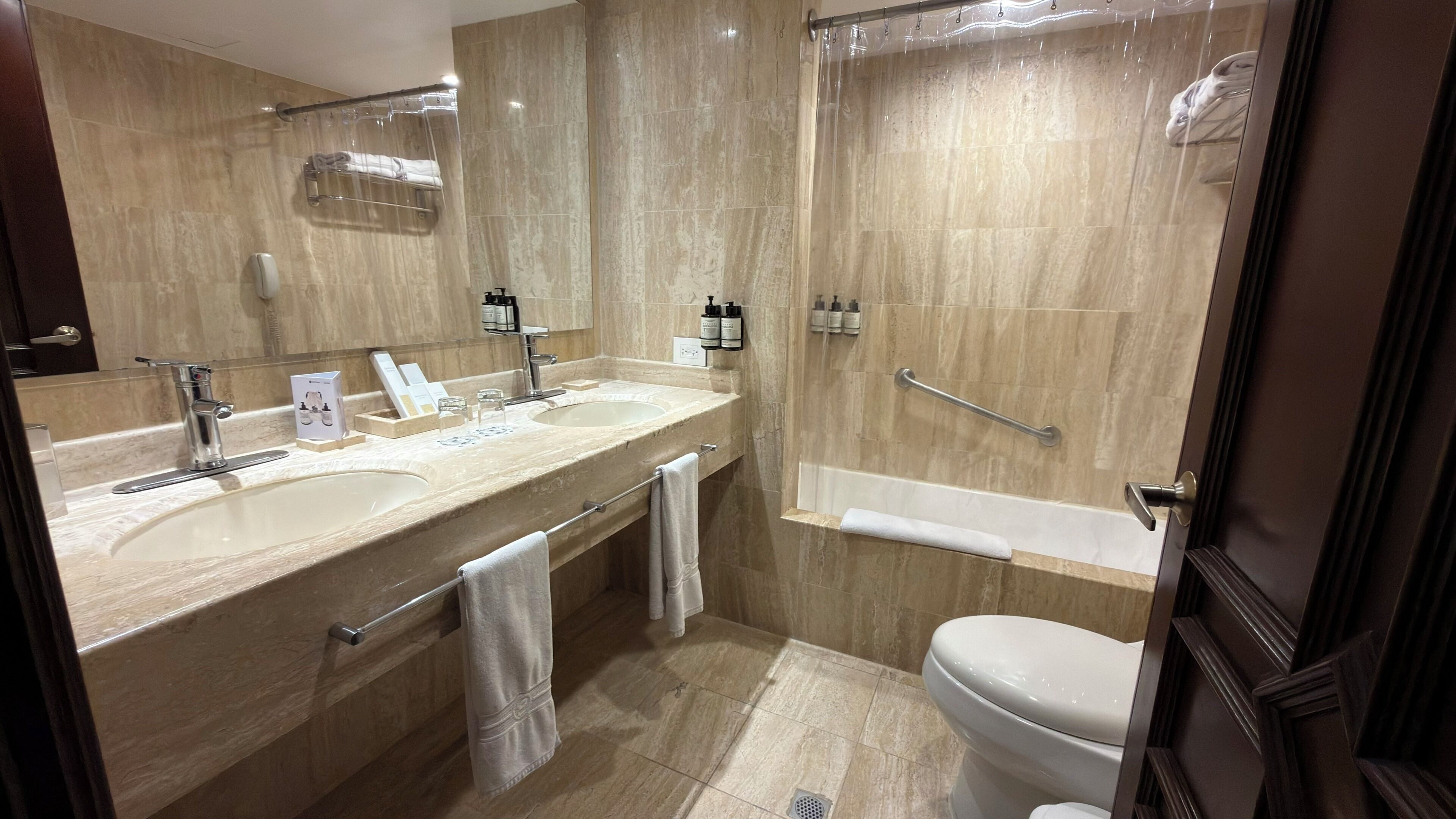 A modern bathroom with two sinks, a bathtub, and a toilet.