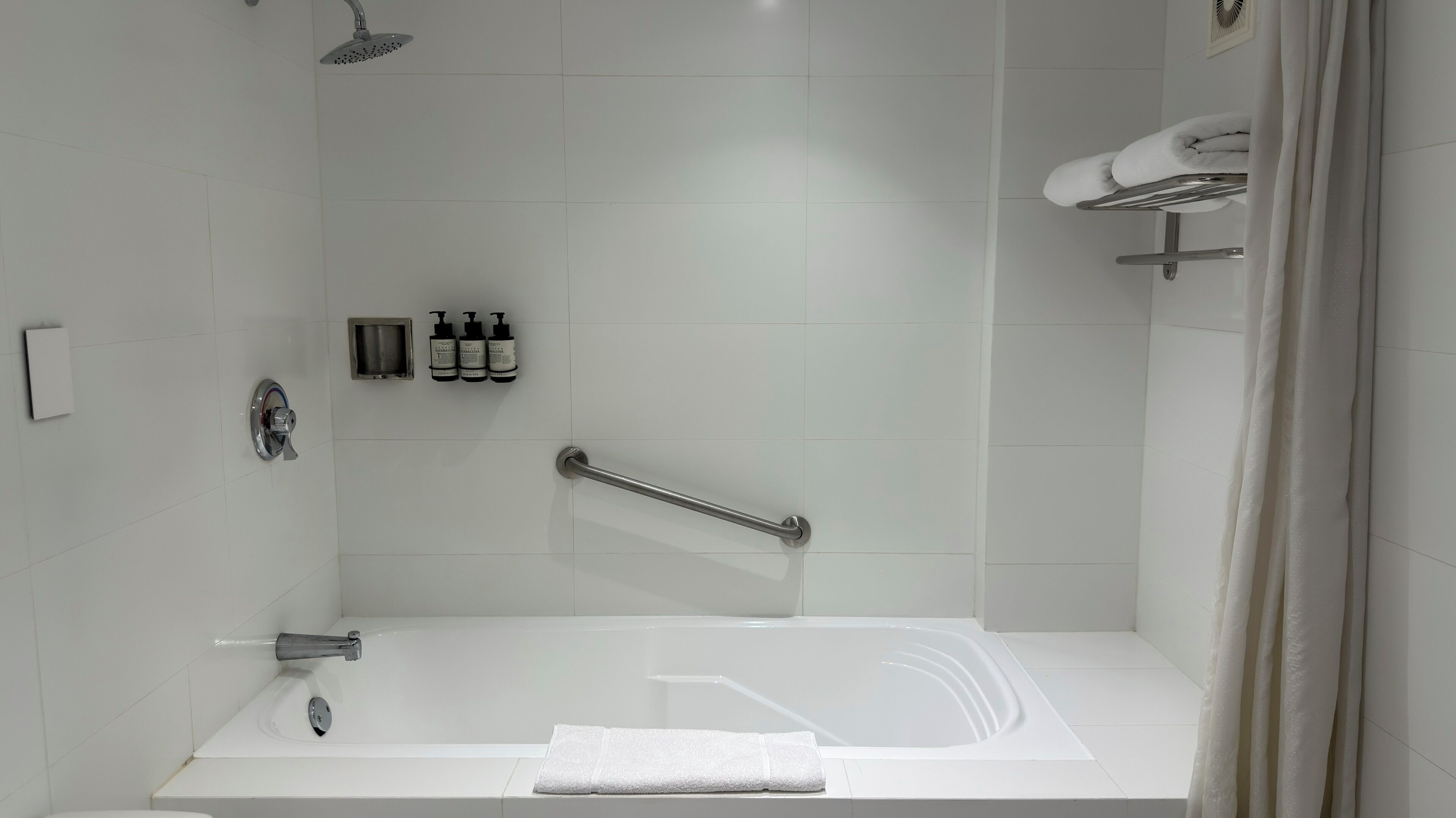 Un baño moderno con una bañera, un cabezal de ducha, un asidero y un perchero para toallas.