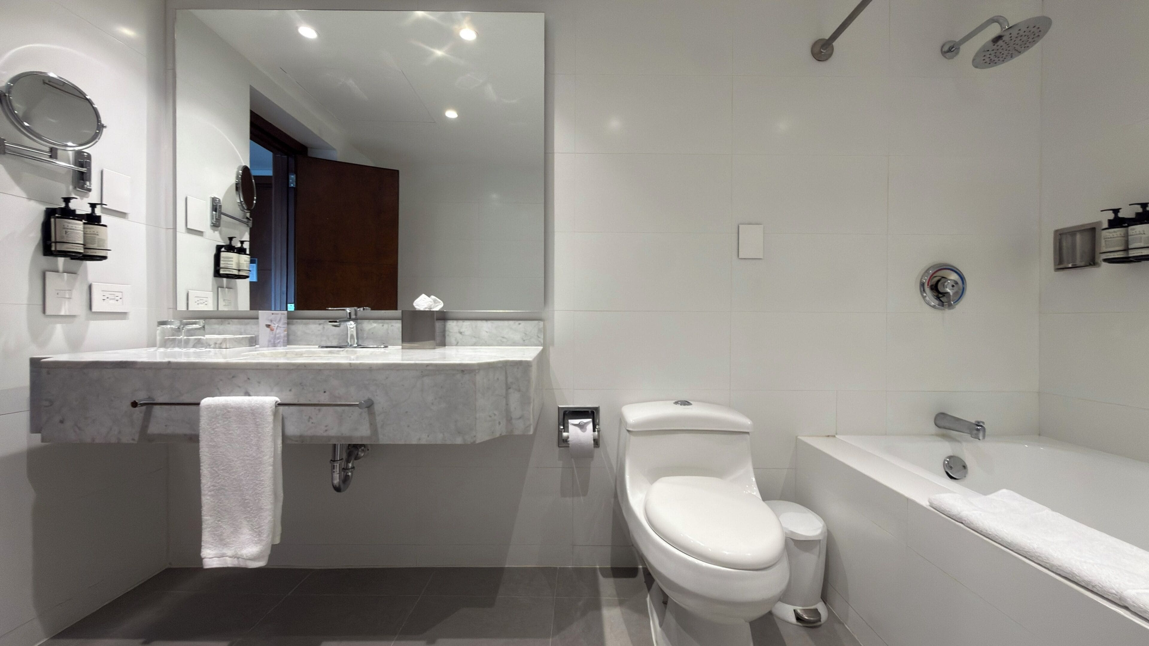 A modern bathroom with a marble sink, a toilet, a bathtub, and a shower.