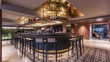 A modern bar area with a circular bar, multiple seating arrangements, and a variety of bottles displayed on shelves.
