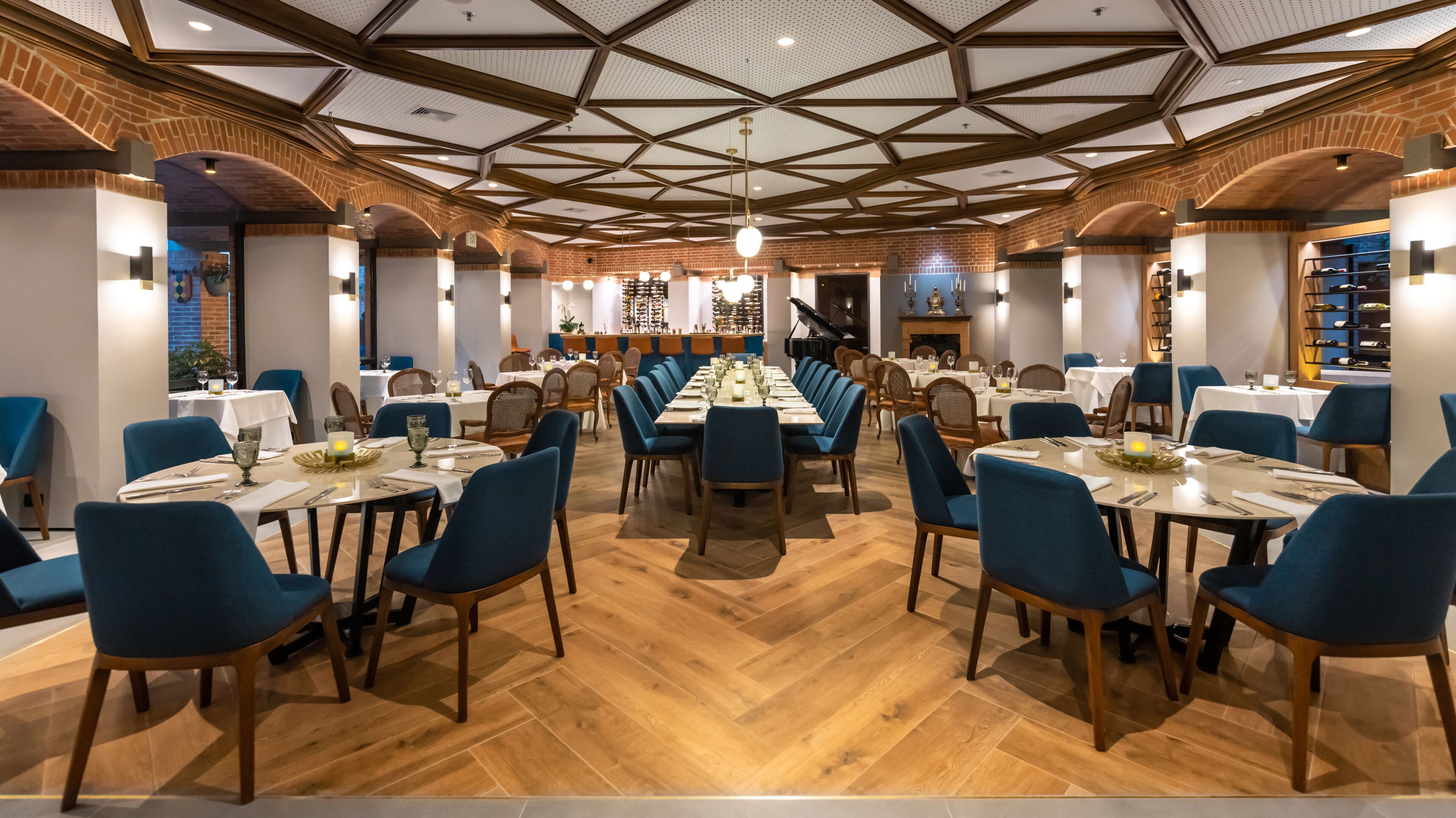 A spacious dining area with long tables, blue chairs, and a high ceiling with wooden beams.