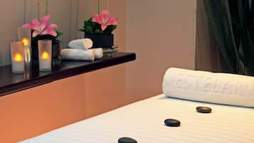 Relax in a serene spa room with a neatly made bed, candles, and a potted plant.