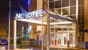 Entrada de un hotel con una galería techada, fachada de vidrio y un cartel que dice "NO OTEI".