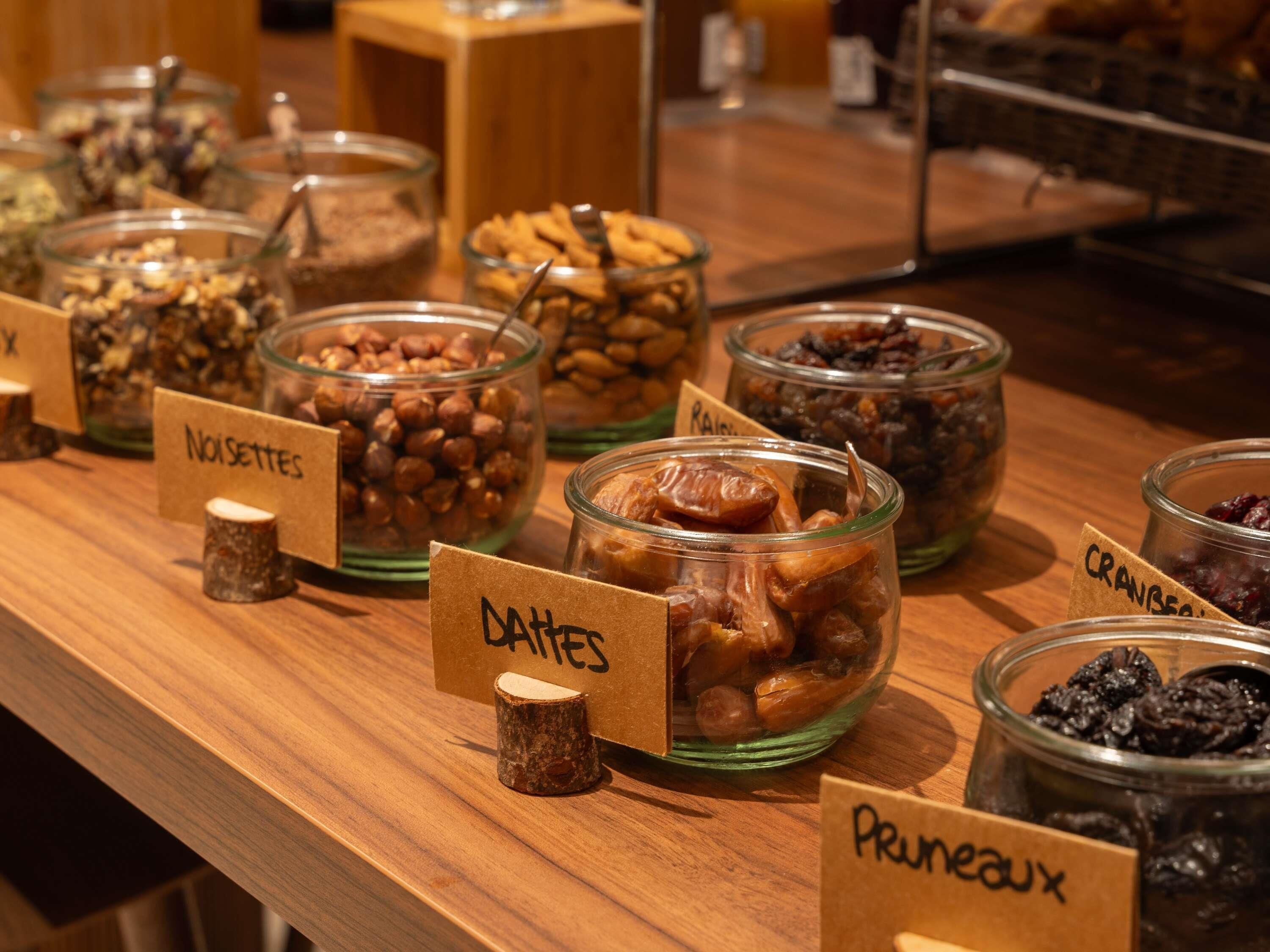 A buffet with labeled containers of nuts, dates, prunes, and other dried fruits.