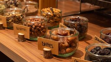 A buffet with labeled containers of nuts, dates, prunes, and other dried fruits.