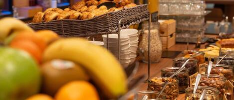 Buffet amb diferents aliments, com fruita, pastissos i una selecció de fruits secs i cereals.