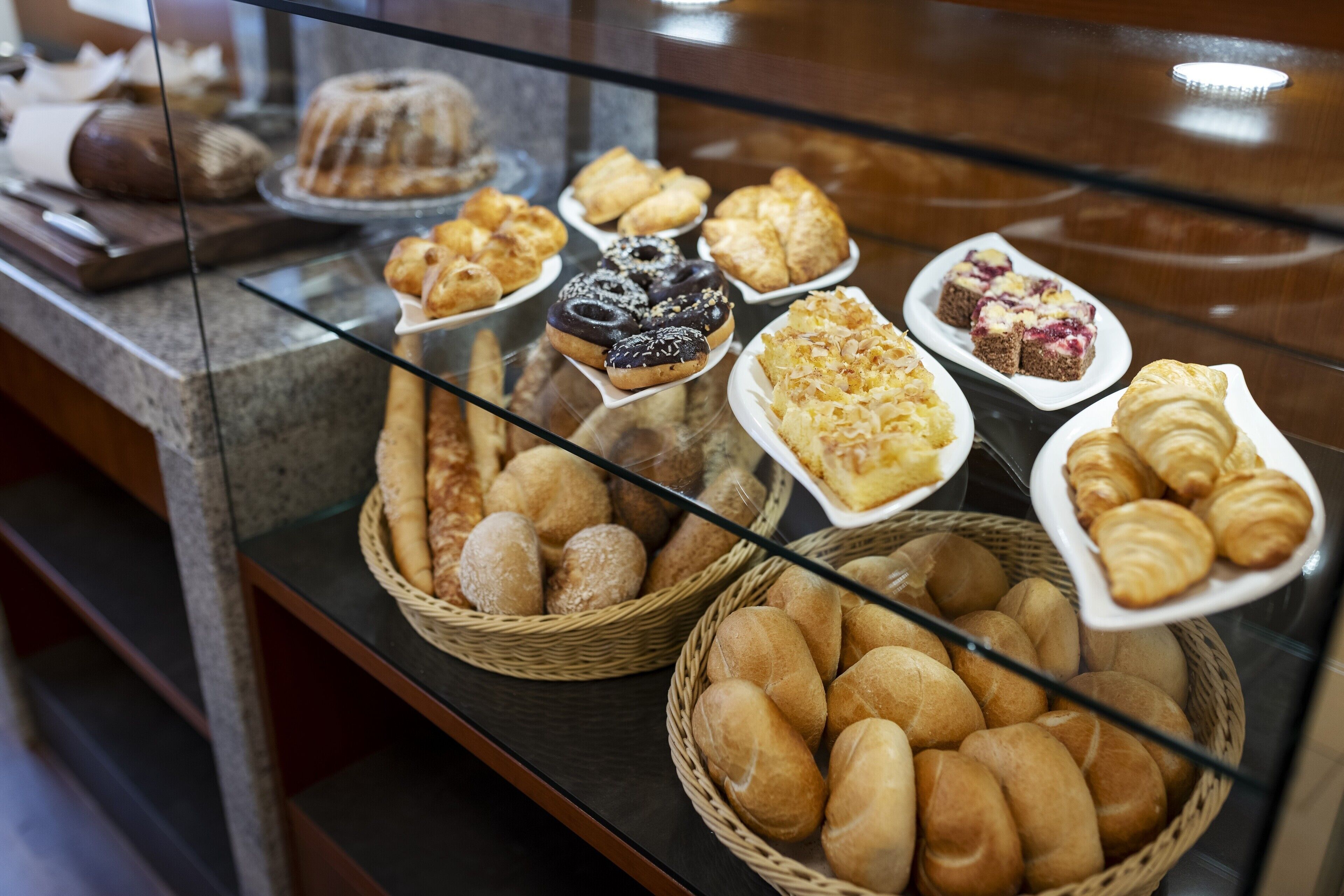 A bakery display with various breads, pastries, and cakes.