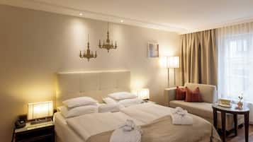 A hotel room with a large bed, a chair, a small table, and a chandelier.