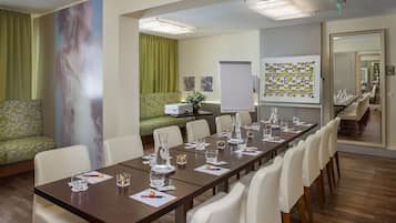 A conference room with a long table, white chairs, and a whiteboard with photos.
