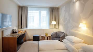 Ein Hotelzimmer mit Bett, Schreibtisch, Stuhl, Nachttisch und Fernseher.