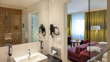 Ein Hotelbad mit Waschbecken, Handtuchspender und Haartrocknern.