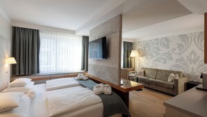 Habitació d'hotel amb un llit gran, un sofà, una televisió i un escriptori.