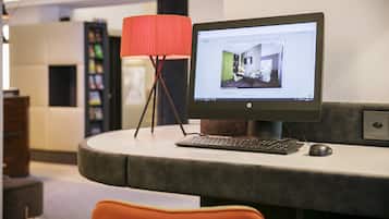 Un espacio de trabajo moderno con un ordenador de escritorio, una lámpara roja y una silla.