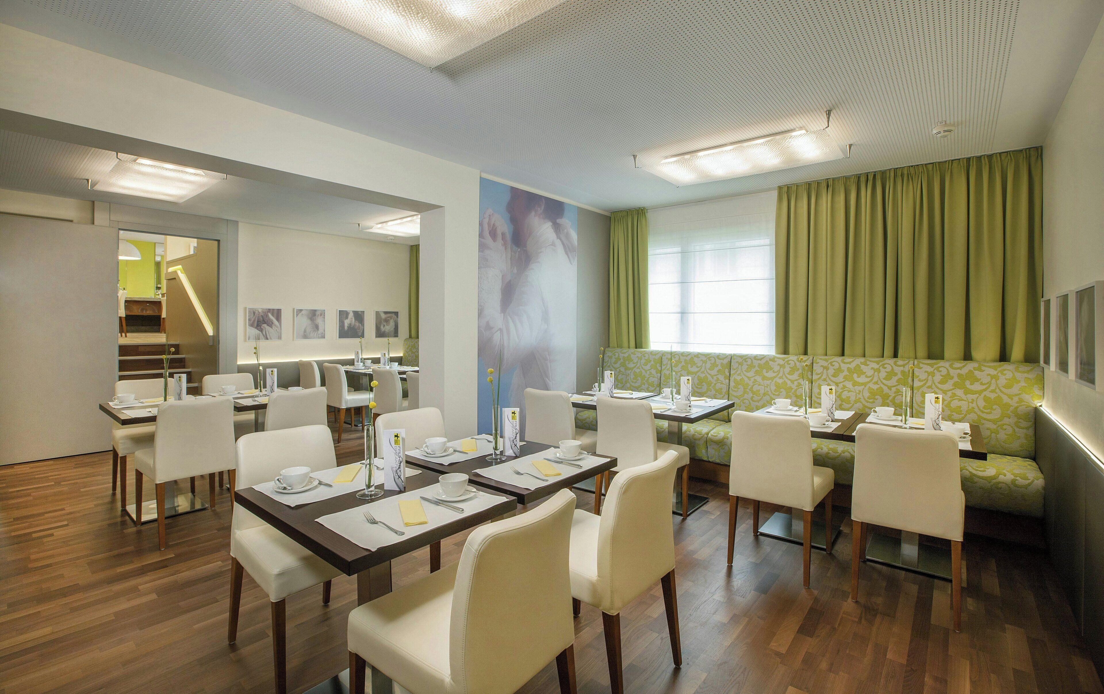 Un comedor de hotel con mesas, sillas y un sofá verde.