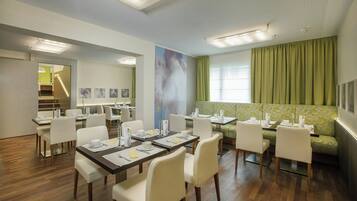 Un comedor de hotel con mesas, sillas y un sofá verde.