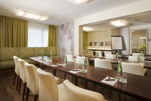 Uma sala de conferência com uma mesa comprida, cadeiras e um quadro branco.