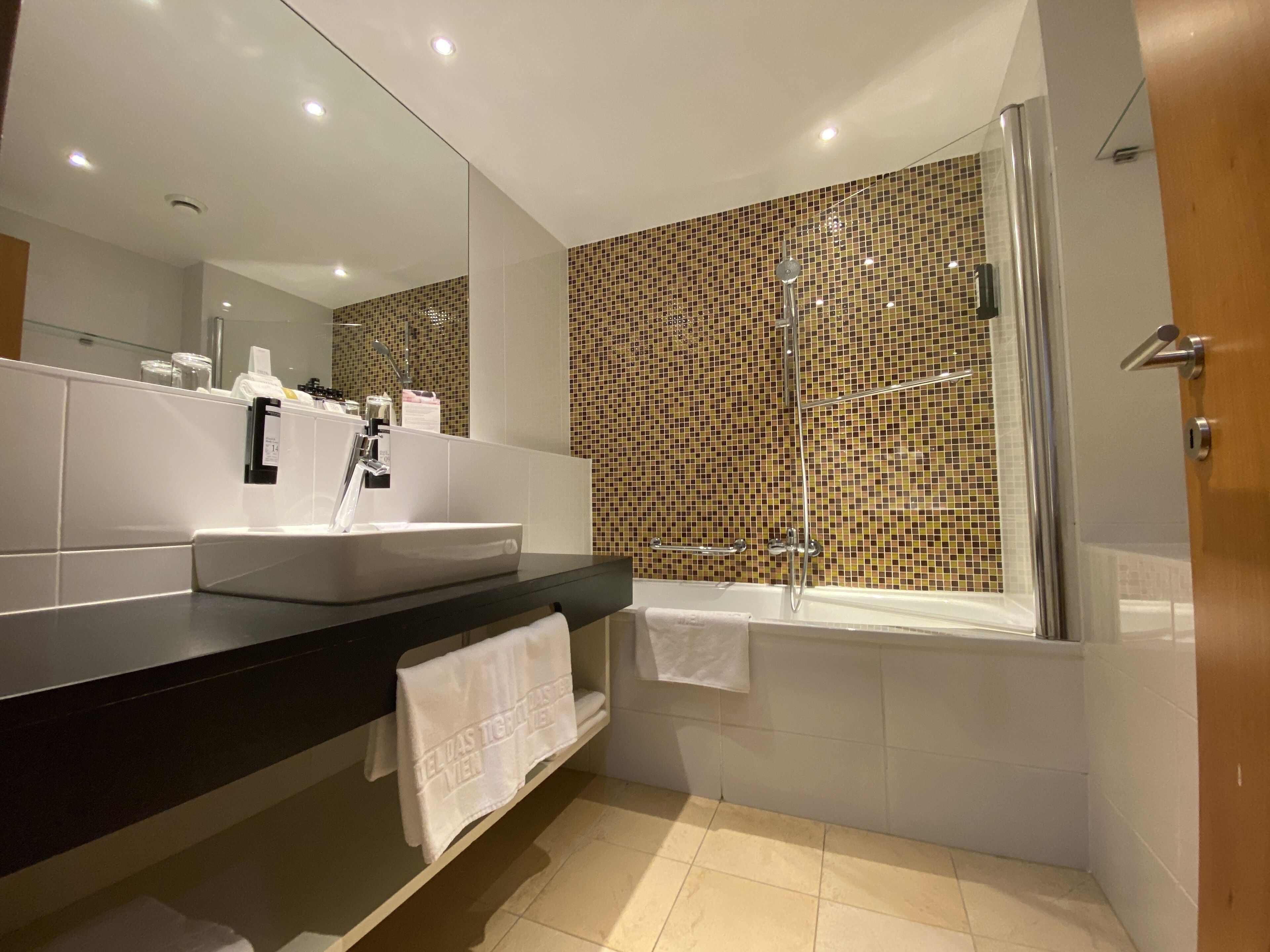 Een moderne badkamer met een grote spiegel, een wastafel, een bad en een douche.