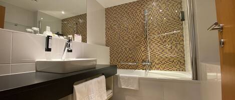 Een moderne badkamer met een grote spiegel, een wastafel, een bad en een douche.