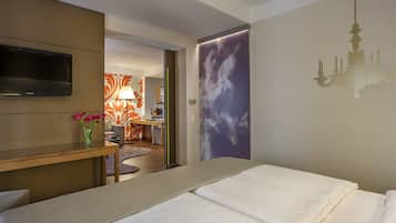 A hotel room with a bed, a TV, a desk with a lamp, and a view of the hallway.