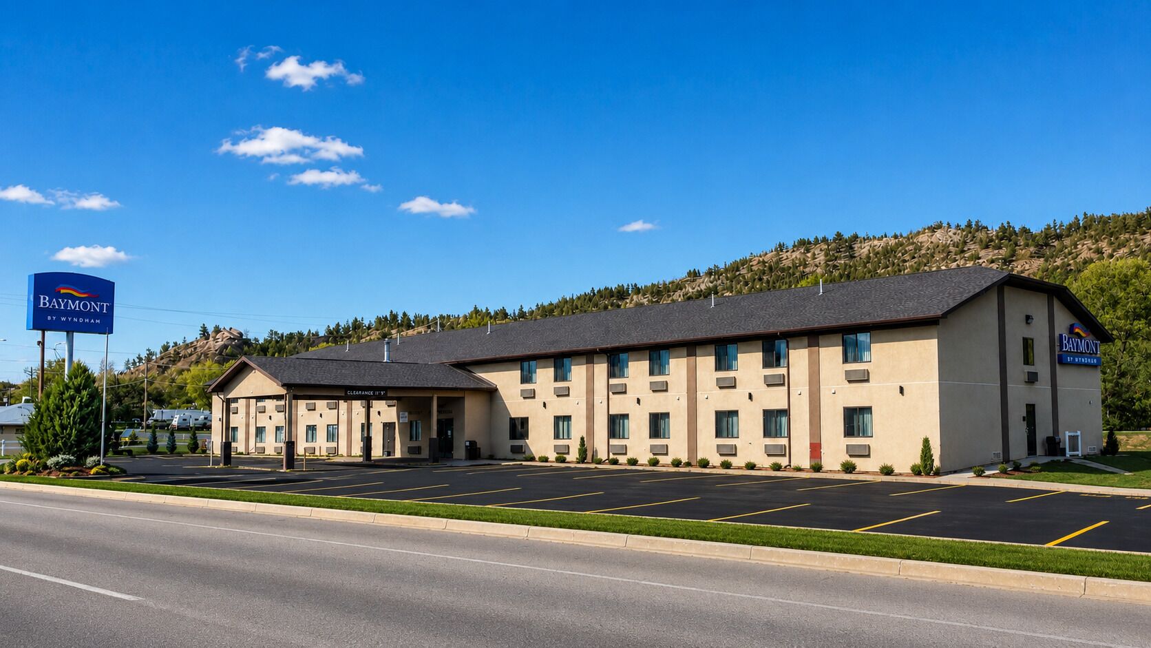 A Baymont by Wyndham hotel with a parking lot and a mountainous backdrop.