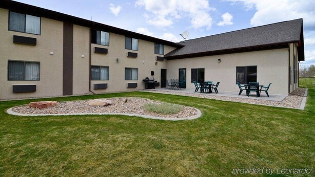 A modern building with multiple windows and a flat roof. There is a patio area with outdoor furniture.