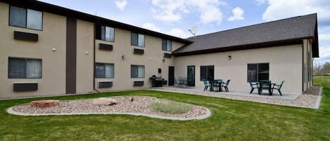 A modern building with multiple windows and a flat roof. There is a patio area with outdoor furniture.