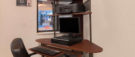 A home office setup with a desk, chair, computer, monitor, printer, and shelves.