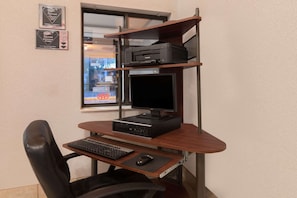 Ein Home-Office-Arbeitsplatz mit Schreibtisch, Stuhl, Computer, Bildschirm, Drucker und Regalen.