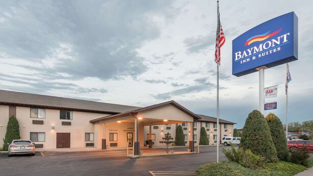 Un Baymont Inn & Suites con recepción, estacionamiento y letrero que indica afiliaciones AAA y HBO.