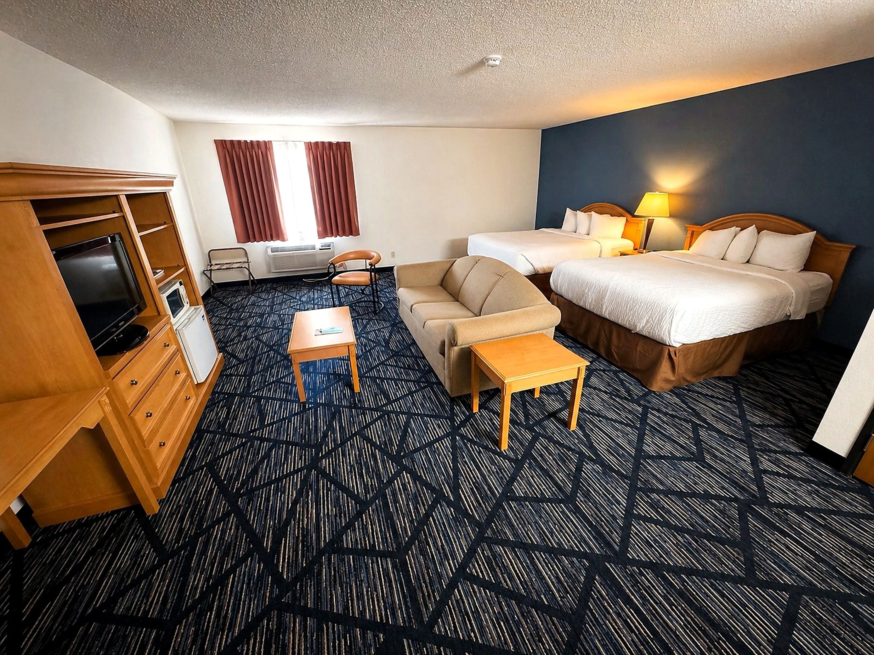 A hotel room with a bed, two bedside tables, a sofa, a TV, and a desk.